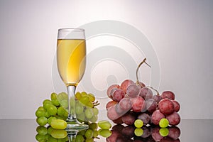 Still life with green and red grapes and wine in a bottle and a glass