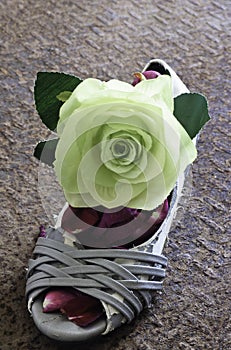 Still life of grungy lady shoe with big green rose