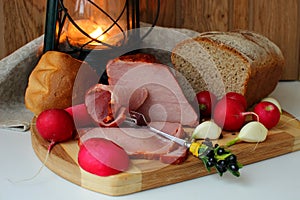 Still life with ham, homemade bread and a lantern