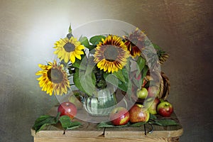 A spectacular bouquet of sunflowers in a vase and apples.