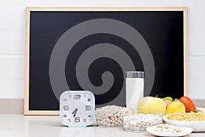 Still life with healthy food, a clock and a blackboard