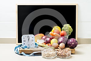 Still life with healthy food, a clock, a tape measure, and a blackboard with copy space