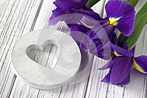 Still life with heart sign iris flowers on white wooden background. Wedding.