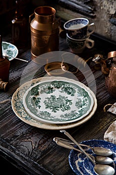 Still life with intage plates with green floral ornaments stand on rustic grey table