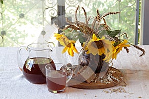 Still-life with kvass (kvas) in a transparent jug and a bouquet