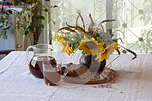 Still-life with kvass (kvas) in a transparent jug and a bouquet