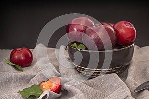 Still life with large black plums in a deep plate