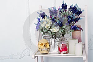 Still life of lavender flowers in a watering can with candles and sculp on a white chair photo
