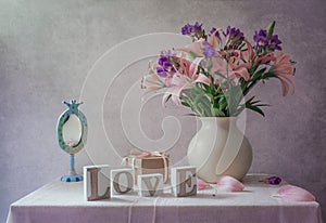 Still life with a lily, freesia, mirror and letters with the word love