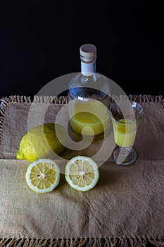 Limoncello traditional italian lemon liqueur with bottle, glass and fresh lemon halves