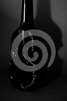 Still life a luxurious glass bottle of cognac, a form of a violin, with an alcoholic drink, abstraction