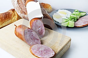 still life made of ham sausage in a loaf on a wooden tray board. A loaf of sausage and sliced pieces of sausage close-up. meat