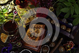 Still life with magic book of spells, runes and cup on witch ritual table.