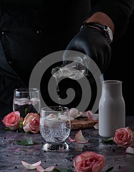 Still life of a man pouring cold sparkling water into a glass with ice. located and a black