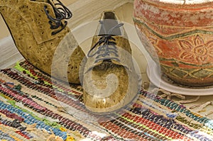 Still life with man shoes, flower pot and woven rug