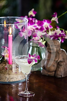 Still life with margarita cocktail, orchid flowers butning candle and hotei