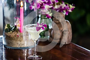 Still life with margarita cocktail, orchid flowers butning candle and hotei