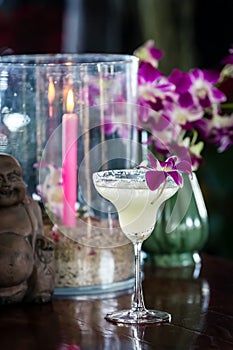 Still life with margarita cocktail, orchid flowers butning candle and hotei