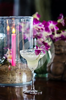 Still life with margarita cocktail, orchid flowers butning candle and hotei