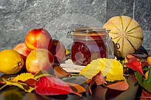 Still life with melon, nectarines, jam and autumn leaves. Autumn harvest season. Fresh delicious healthy fruits, contain