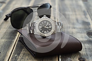 Still life men`s accessories with  watch, leather wallet, and sunglasses on old grunge wooden table. Set of men`s accessories fo photo