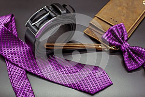 Still life with men`s casual outfits tie, bow tie, belt, boots, watch with leather accessories on a black background, beauty an