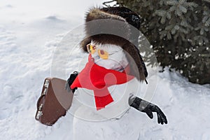 Still life of Merry Christmas and a Happy New Year. A happy snowman in a fur sable hat, red mincemeat and sunglasses with a suitca photo