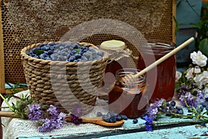 Still life with natural honey, honeycomb cut in pieces and honeysuckle berry with flowers on wooden background outside.