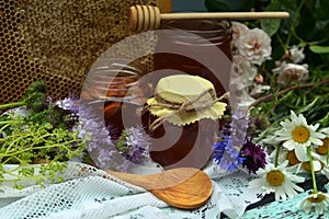 Still life with natural honey in jar, dipper, flowers and stick on wooden background