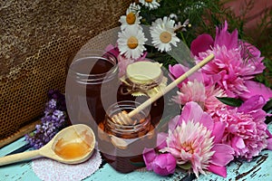 Still life with natural honey in jar, dipper, peony and stick on wooden background