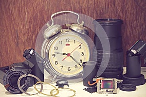 Still life with old broken alarm clock, broken camera lens, came