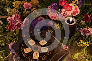 Still life with old runes, zodiac circle, black candle, flowers and ritual objects
