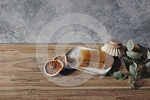 Still life of organic handmade soap bar, wooden brush and dry lemons ruit and eucalyptus on wooden table. Spa, herbal