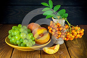 Still life of peach grapes and rowan berries on a wooden table after harvest