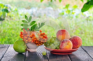 Still life of peach grapes and rowan berries on a wooden table after harvest