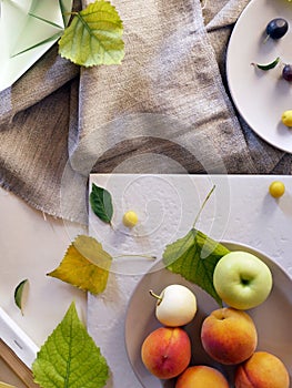 Still life of peaches, apples, leaves on a light background, top view