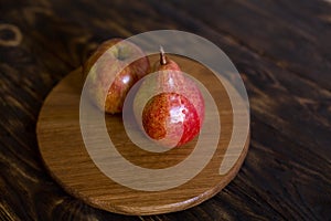 Still life. Pear and apple on a brown background, on a cutting board.