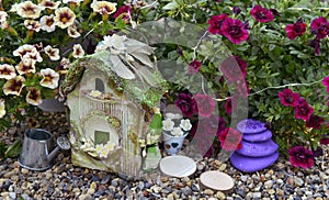 Still life with petunia flowers and beautiful fairy cottage in the garden