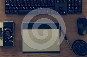 Still life of photographer desk in home office interior. Professional photo media working equipment, camera body, lenses, monitor