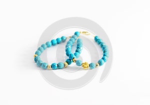 Still life photography of turquoise gemstone bracelets with golden beads and cross