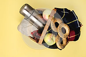 Still Life Picnic Basket with Warm Blanket Apples and Thermos Autumn Yellow Background Top View Copy Space