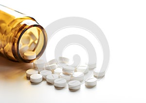 Still life with pile of white pills or tablets and glass bottle or glass photo