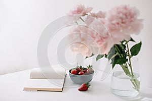 Still life with pink peony flowers and open  book. Summer concept.  fresh flowers at home, cozy interior