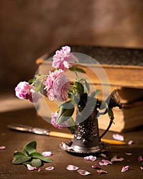 Still life with pink roses and books in the background