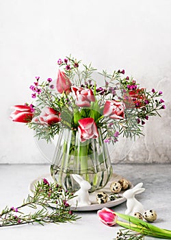 Still life with pink, white tulips and purple wax flower flowers in the old vintage glass vase.