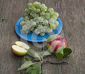 Still life a plate with grapes and two apples on a table