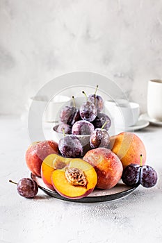 Still life of plums and peaches on a white background