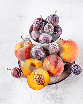 Still life of plums and peaches on a white background