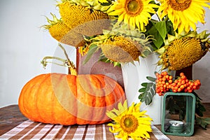 Still life with pumpkin, a bouquet of sunflowers and a white vase, candlesticks and red rowan, hello autumn concept