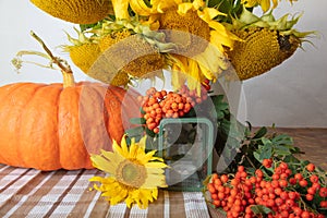 Still life with pumpkin, a bouquet of sunflowers and a white vase, candlesticks and red rowan, hello autumn concept